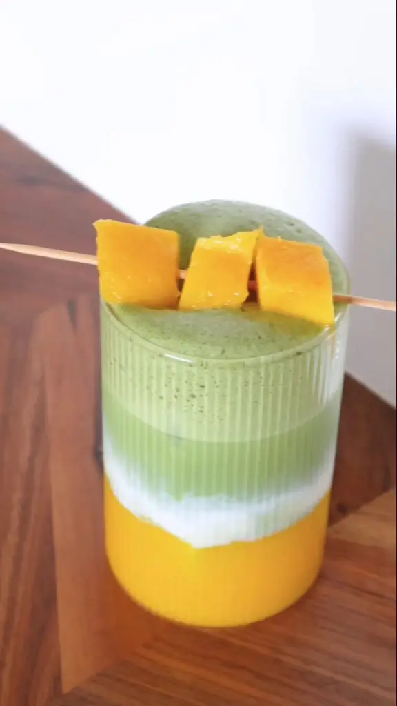 Layered green and yellow drink topped with skewered fruit cubes