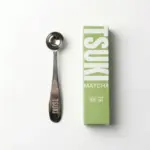 Metal Tsuki measuring spoon beside a green and white Tsuki Matcha box