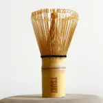 Upright bamboo matcha whisk with fine curled tines and TSUKI engraved on the handle