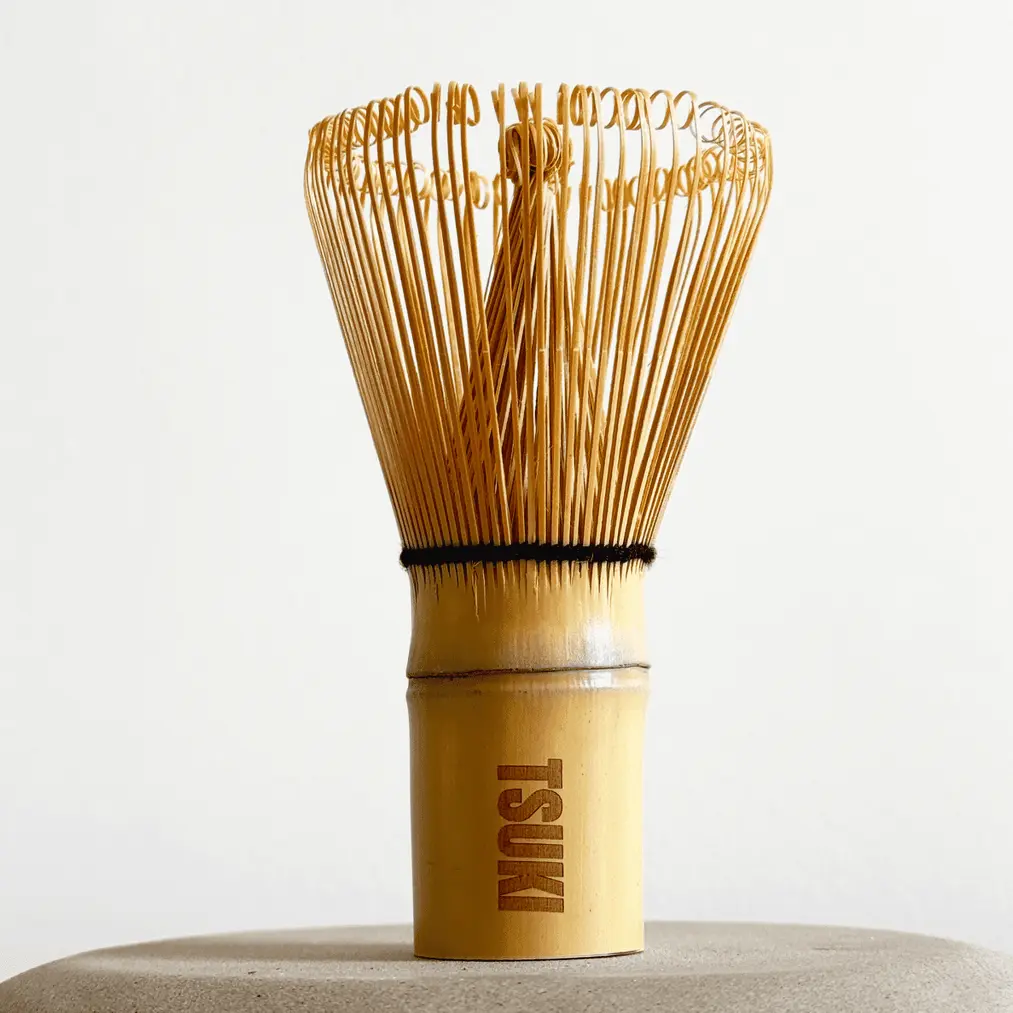 Upright bamboo matcha whisk with fine curled tines and TSUKI engraved on the handle