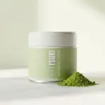 Green Tsuki Matcha Original tin beside a small mound of matcha powder