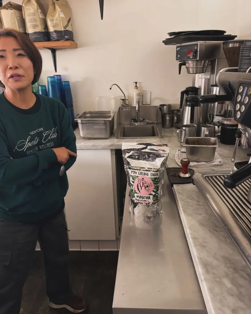 Man Eating Tiger matcha bag on a café counter beside espresso equipment