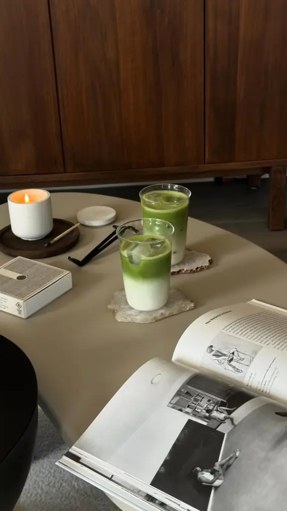 Two iced matcha lattes beside a candle and open book
