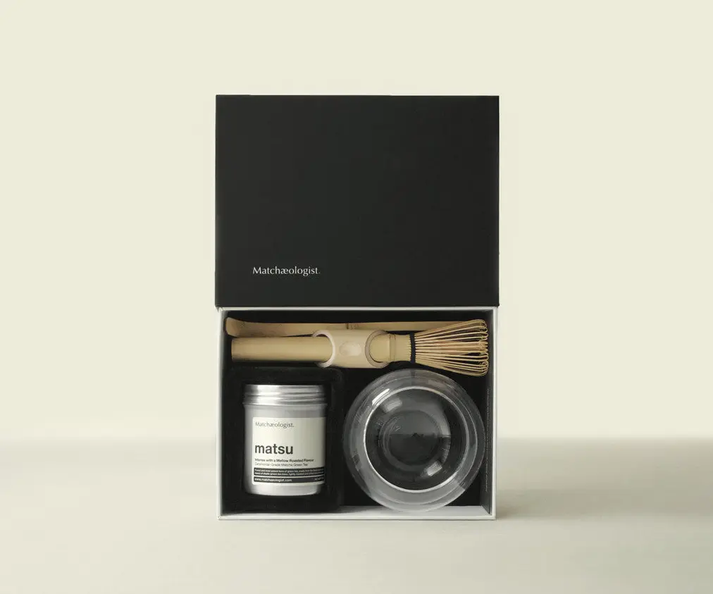 Open Matchæologist kit with Matsu matcha tin, bamboo whisk, scoop, and clear bowl