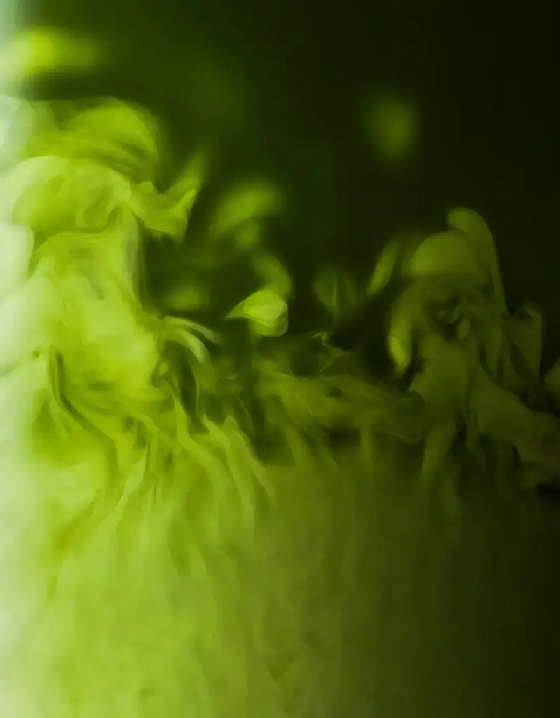 Close-up of bright green matcha swirling into a dark liquid