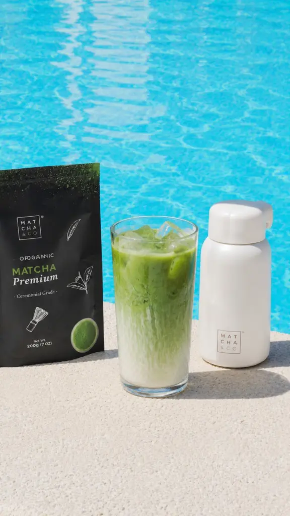 Tall iced green drink beside a Matcha Premium pouch and white bottle by a pool