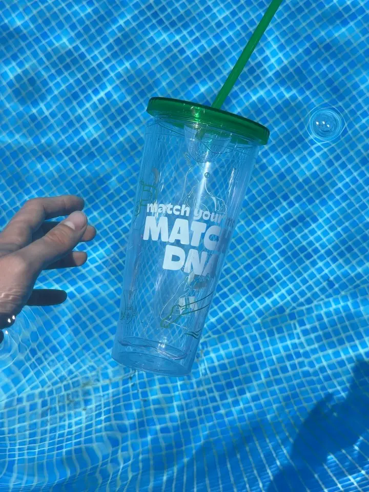 Clear Matcha DNA tumbler with green lid and straw held underwater