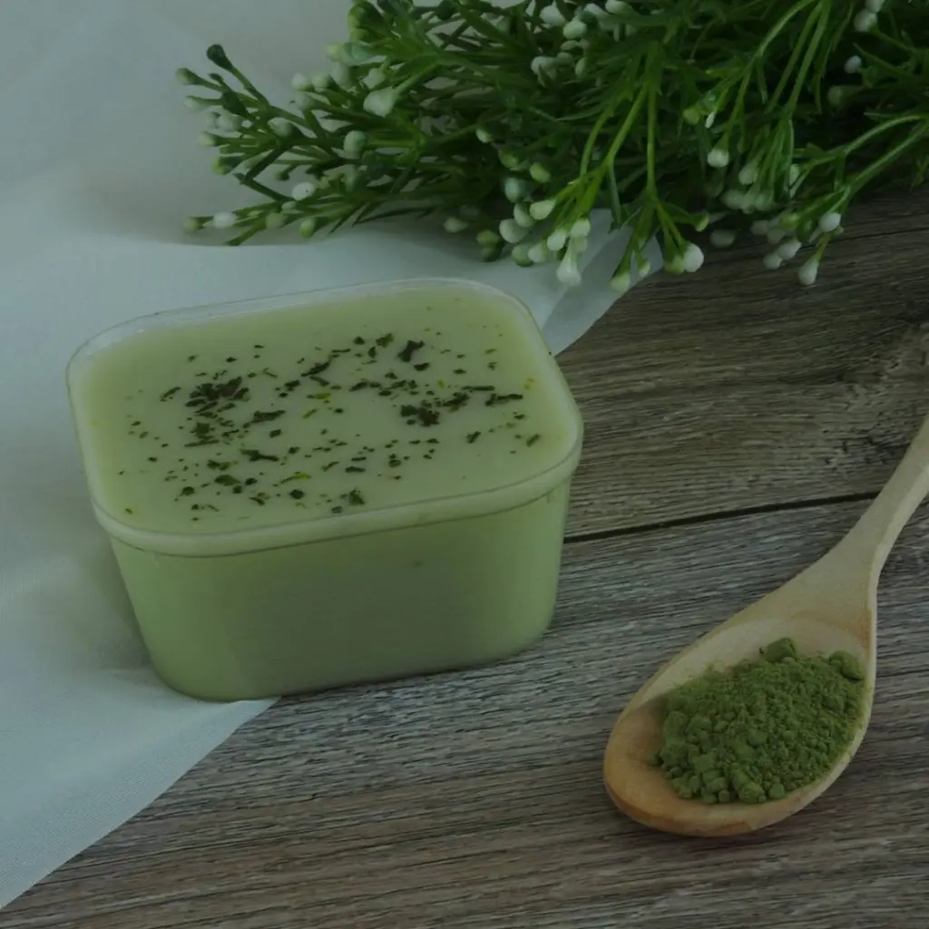 Pale green dessert beside a wooden spoon filled with matcha powder