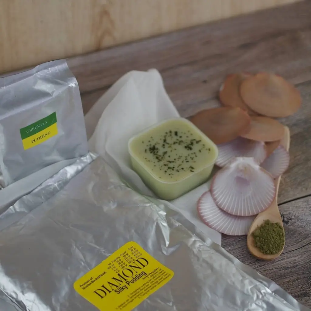 Green tea pudding with silver pouches, shells, and a spoonful of green powder