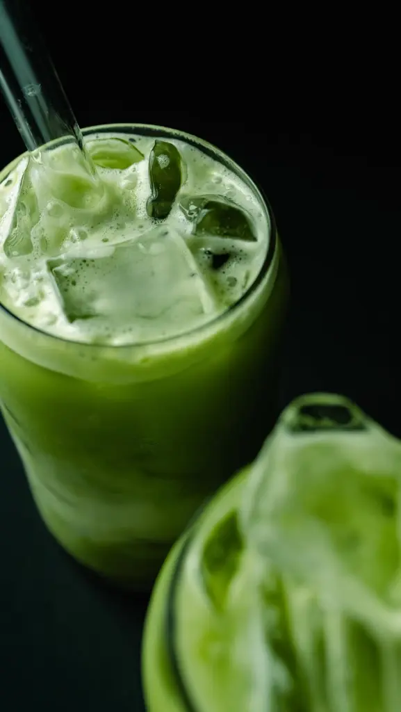 Two glasses of foamy green iced matcha with clear straws