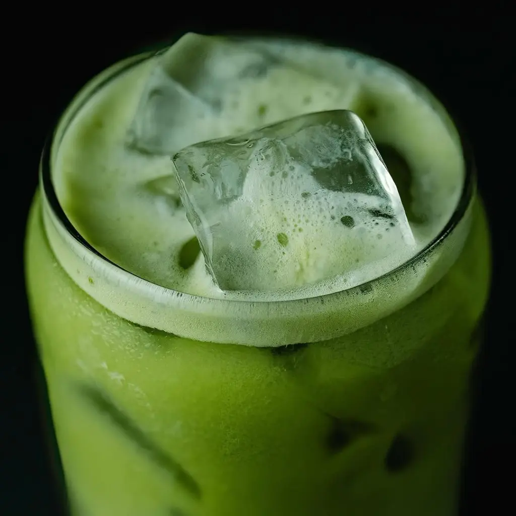 Frothy green drink with large ice cubes in a glass