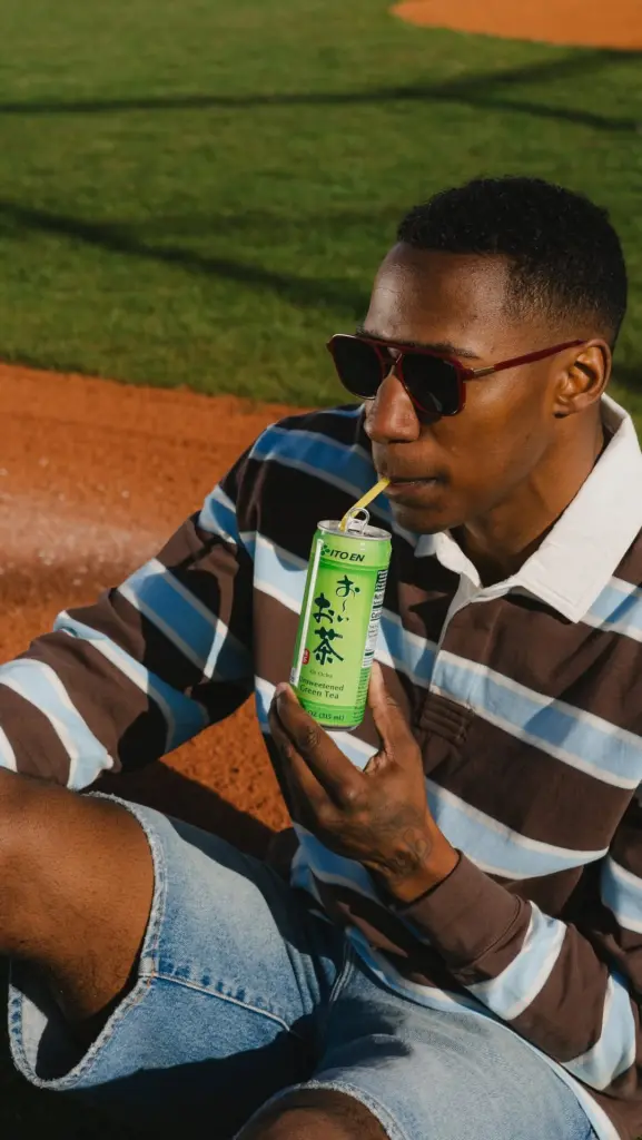 Man in sunglasses sipping canned green tea through a straw