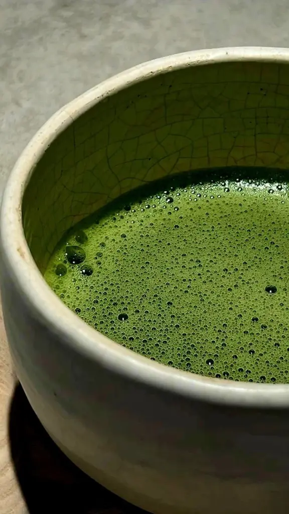 Close-up of frothy green matcha in a ceramic bowl