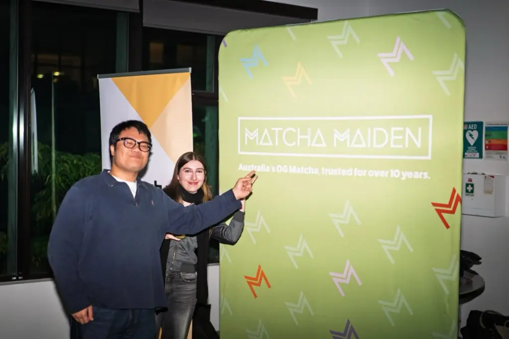 Two guests posing beside a large green Matcha Maiden display