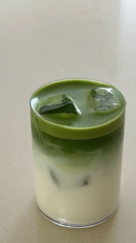 Layered green and white iced matcha latte in a clear glass