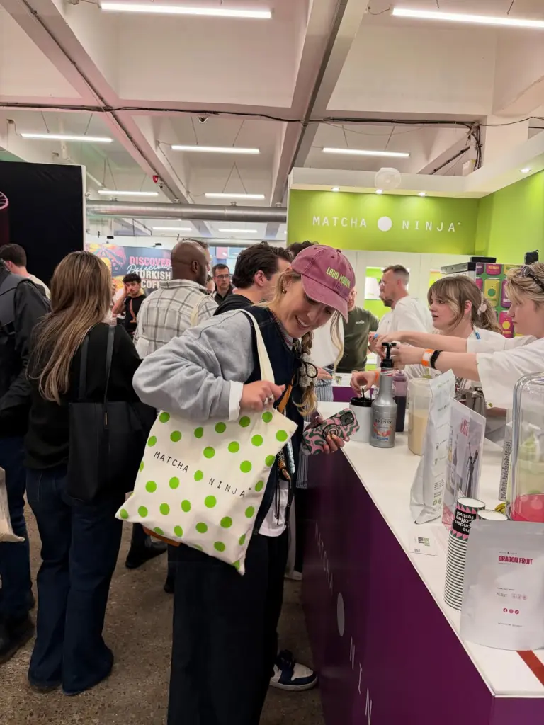Smiling booth visitor carrying a green polka-dot Matcha Ninja tote