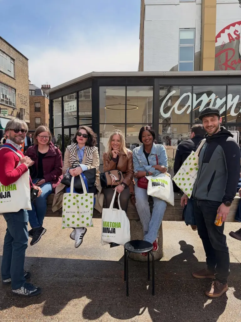 Six adults posing outdoors with cream Matcha Ninja tote bags