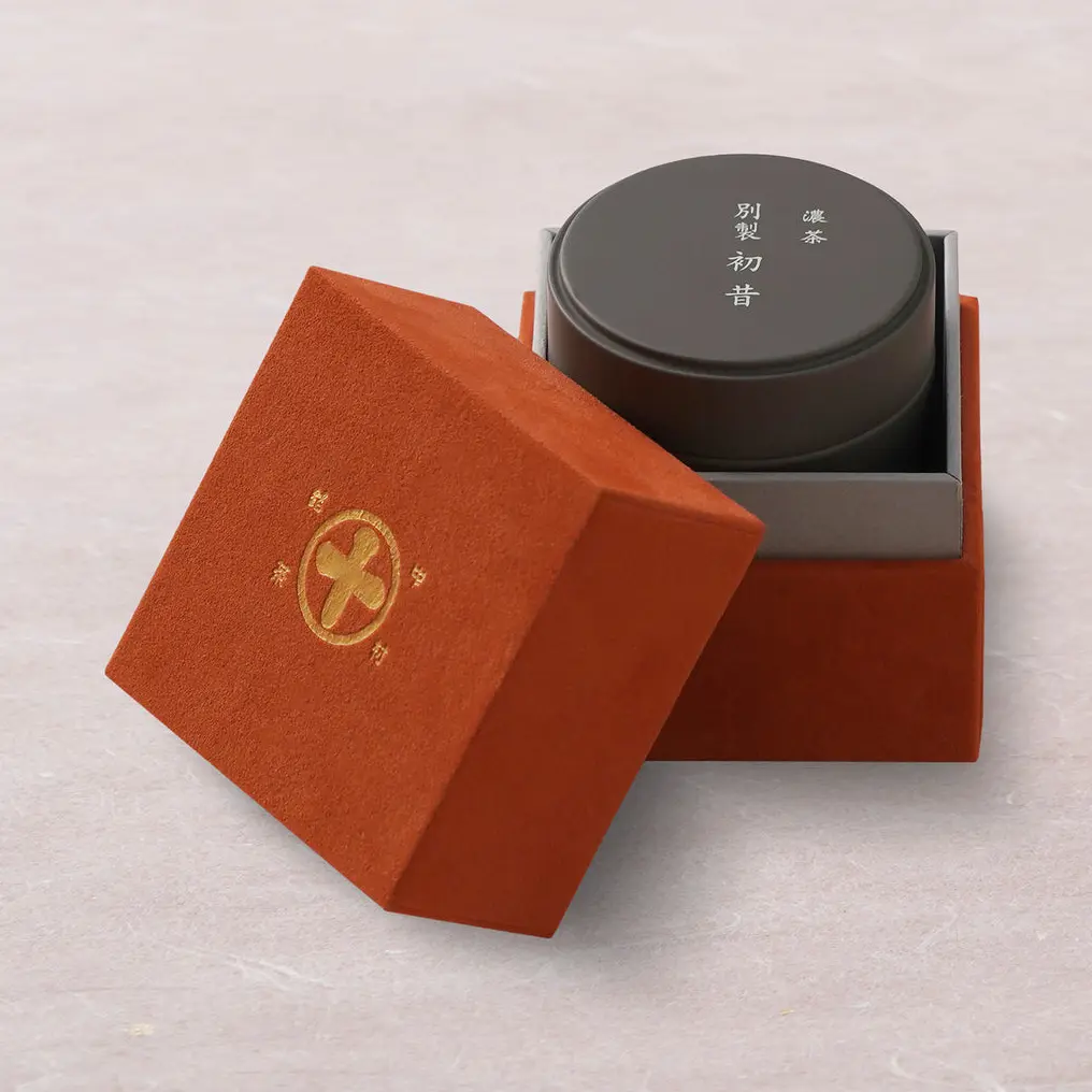 Dark round matcha tin inside an open red presentation box with a gold emblem