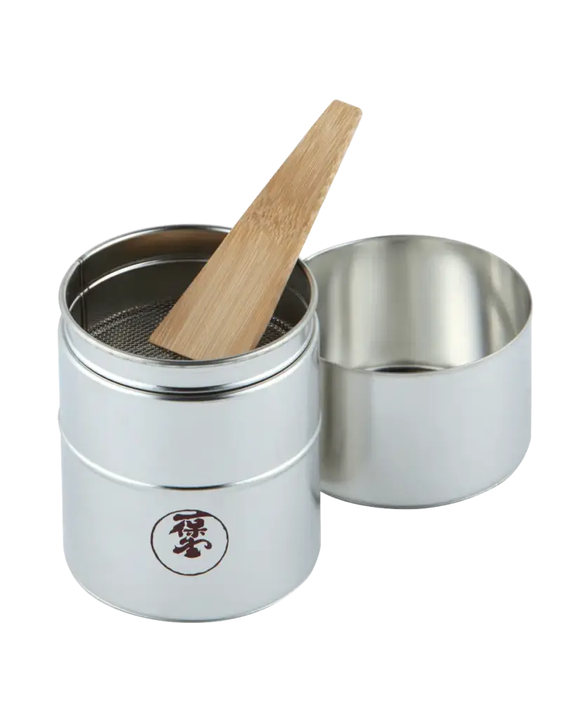 Open silver matcha sieve with mesh insert, wooden spatula, and lid beside it
