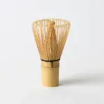 Bamboo matcha whisk standing upright against a plain white background