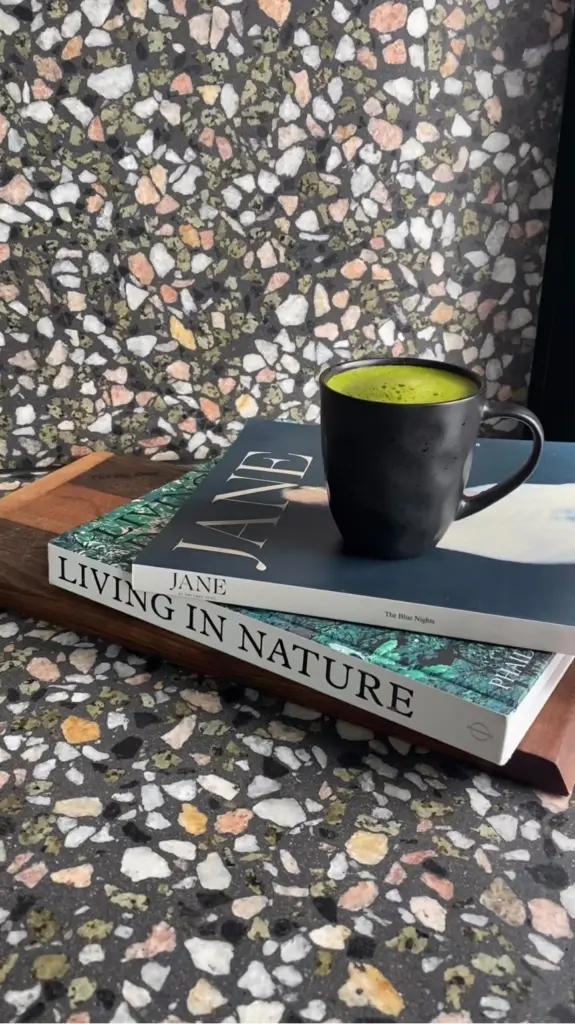 Black mug of bright green matcha resting on two stacked books