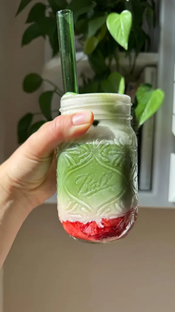 Hand holding a mason jar with red, white, and green drink layers