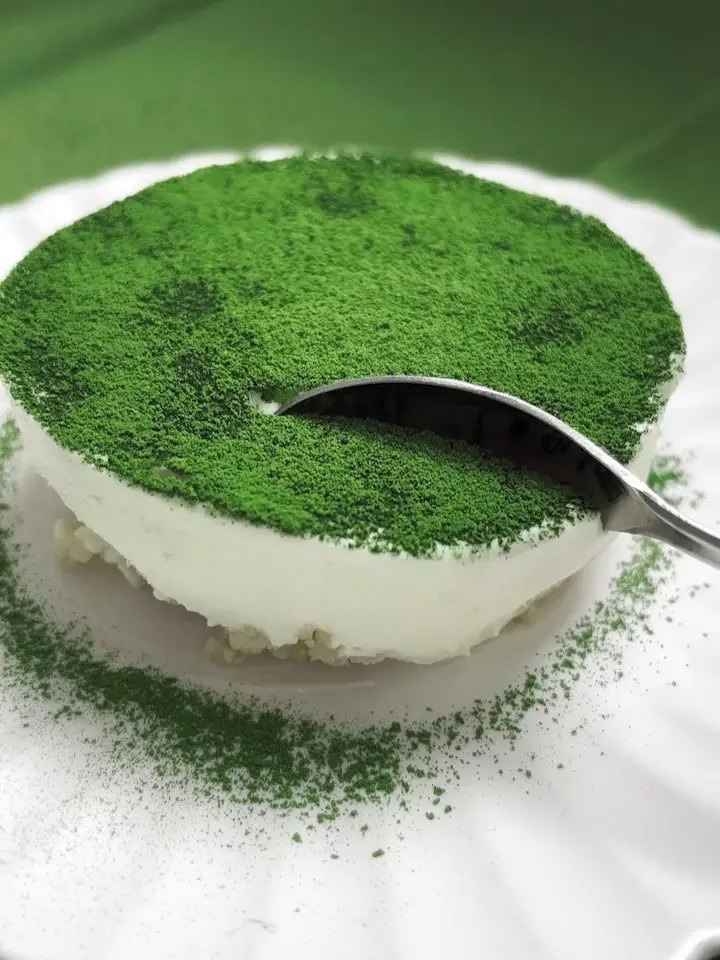 Spoon pressed into a round white dessert dusted with green powder
