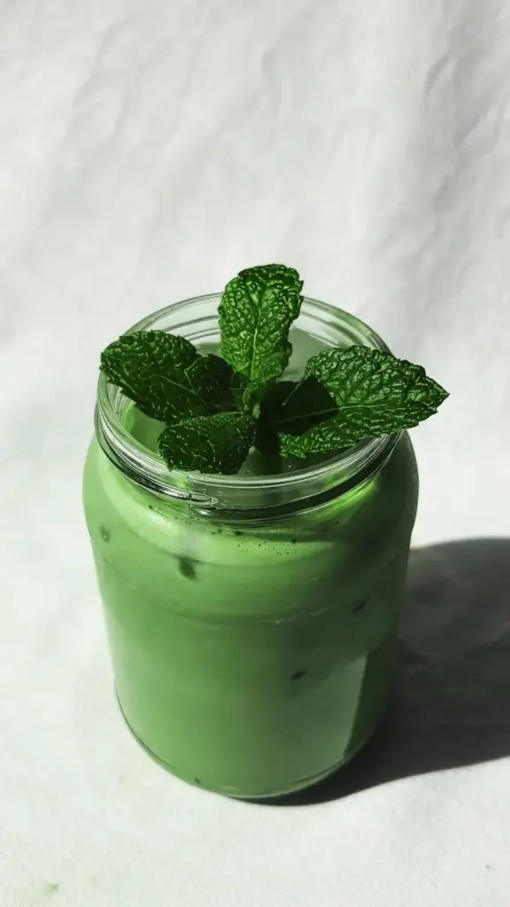 Iced green drink in a glass jar topped with fresh mint