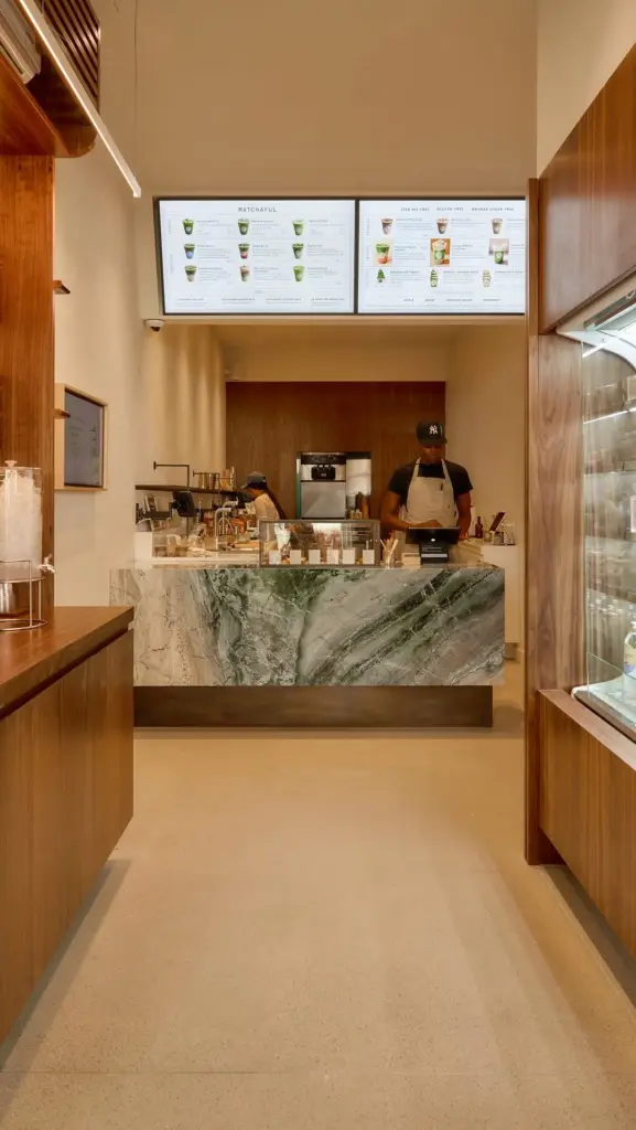 Staff working behind a marble café counter beneath Matchaful menu screens