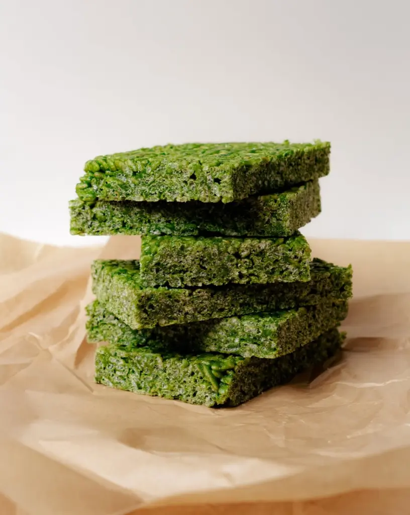 Stacked green crispy treat squares on parchment paper