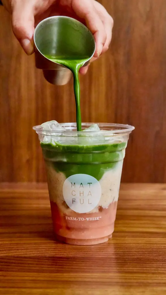 Green matcha poured into a layered iced drink in a Matchaful cup