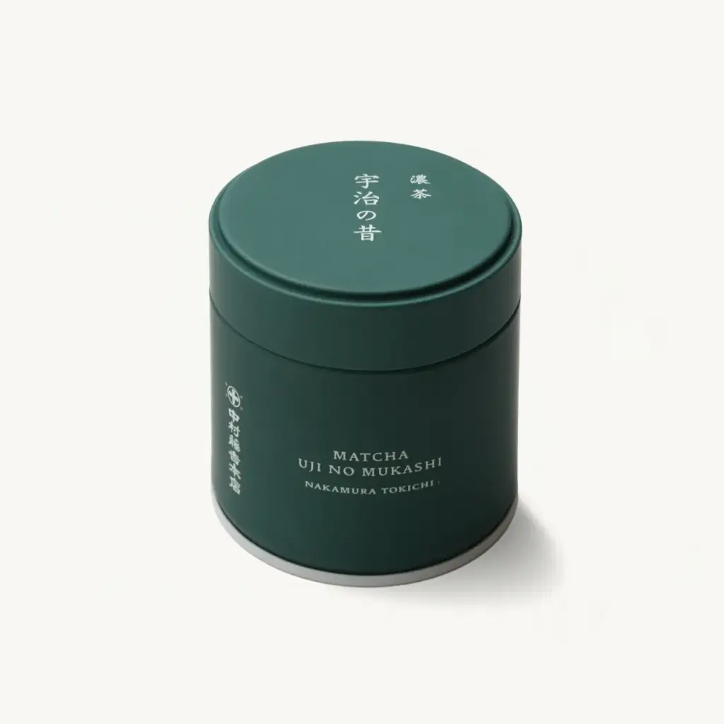 Closed dark green matcha tin labeled Matcha Uji No Mukashi, Nakamura Tokichi, photographed at an angle on a cream background