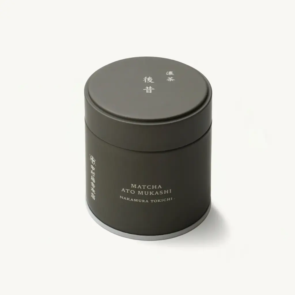Dark olive cylindrical matcha tin labeled Matcha Ato Mukashi Nakamura Tokichi, lid on, shown at an angle on a cream background