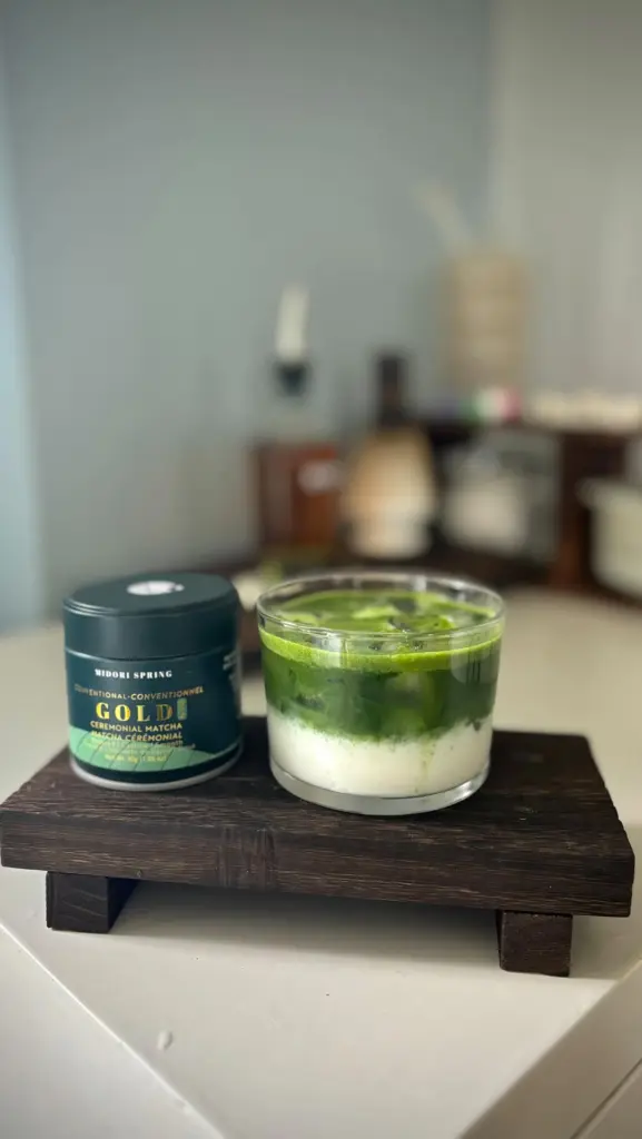 Layered iced green matcha drink beside a Midori Spring Gold tin