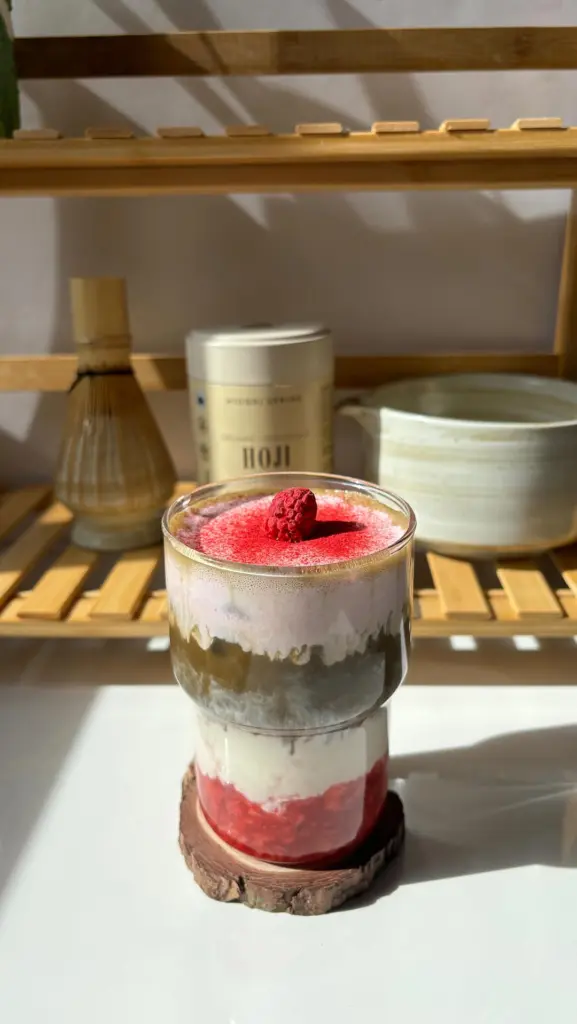 Pink and brown layered drink topped with a raspberry
