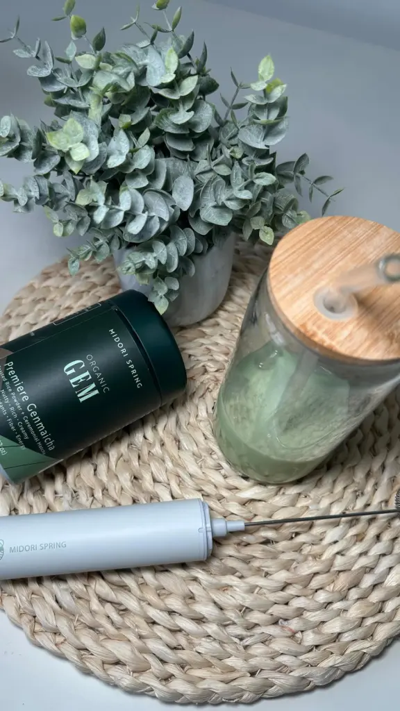 Midori Spring Premiere Genmaicha tin beside a pale green drink and handheld frother