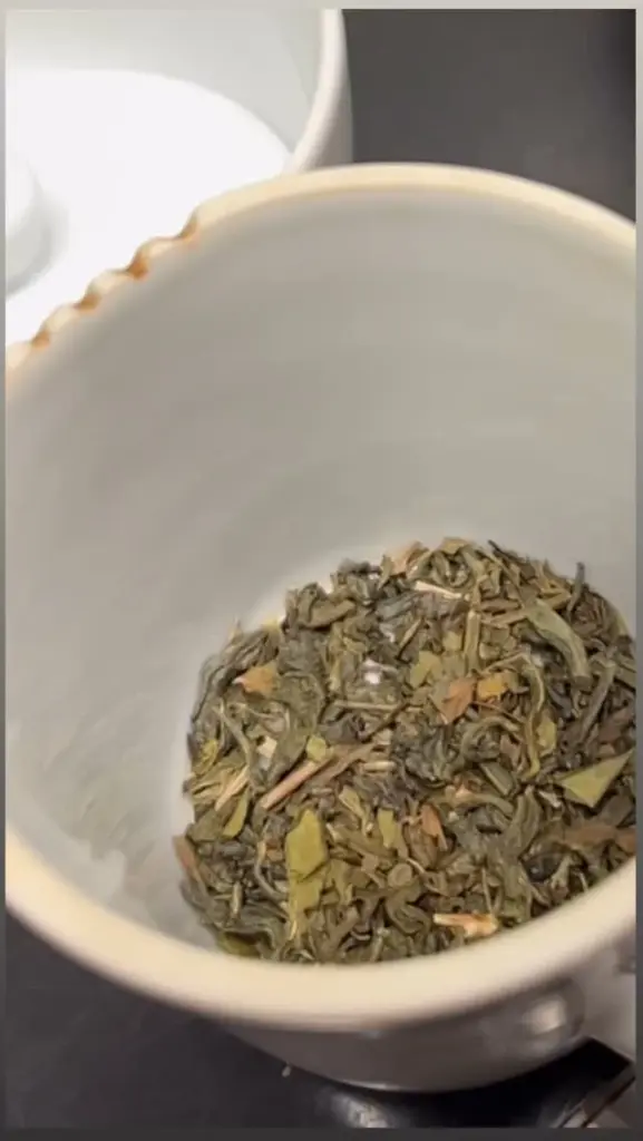 Loose dried tea leaves gathered at the bottom of a white ceramic vessel