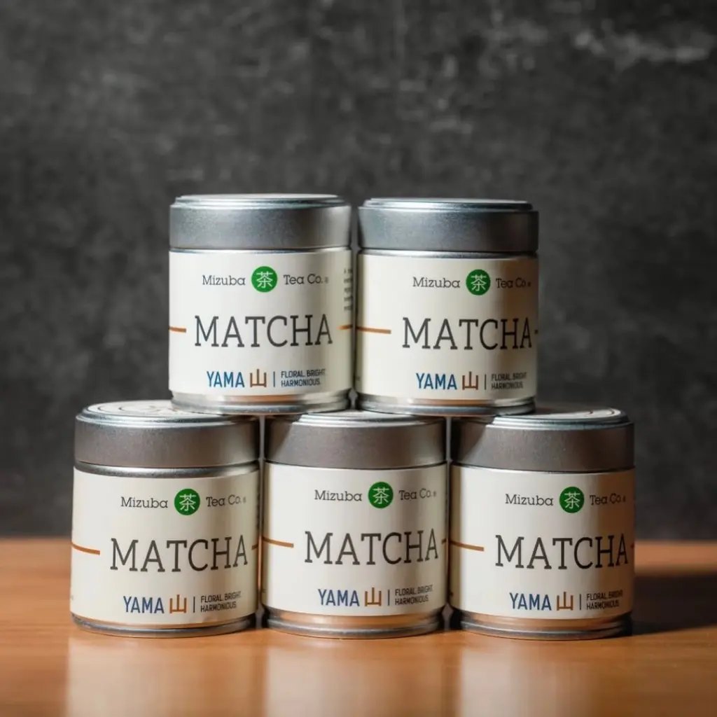 Five Mizuba Yama Matcha tins stacked on a wooden surface