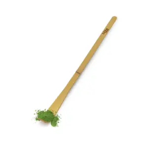 Long bamboo matcha spoon holding green powder on a white background