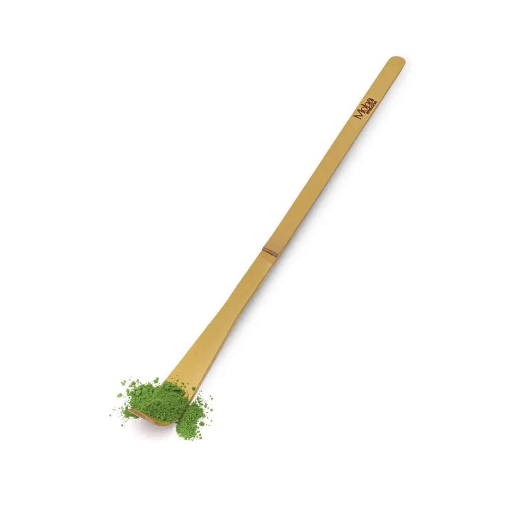 Long bamboo matcha spoon holding green powder on a white background