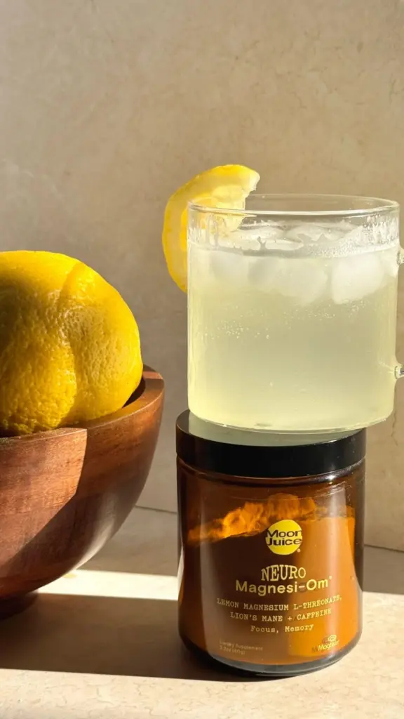 Neuro Magnesi-Om jar topped with an iced lemon drink beside fresh lemons