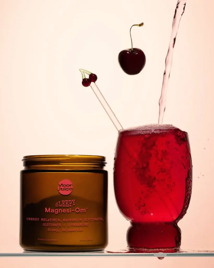 Sleepy Magnesi-Om jar beside a red cherry drink with liquid pouring into the glass