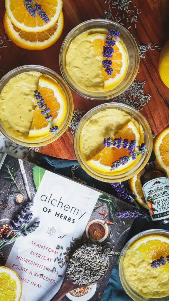 Glass bowls of creamy dessert topped with orange slices and lavender sprigs