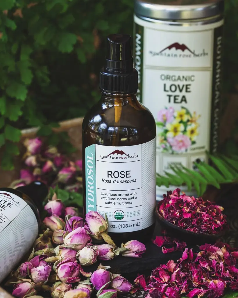 Mountain Rose Herbs rose hydrosol bottle surrounded by dried rosebuds and petals