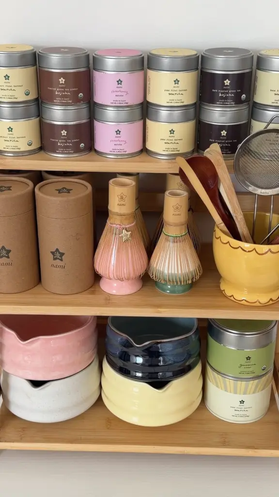 Shelves filled with Nami tea tins, bamboo whisks, bowls, scoops, and a strainer