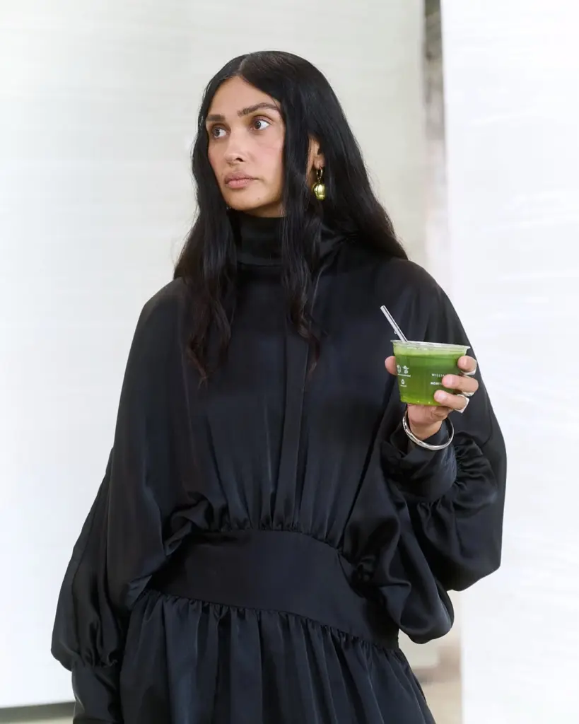 Guest in a black dress holding a clear cup of bright green drink