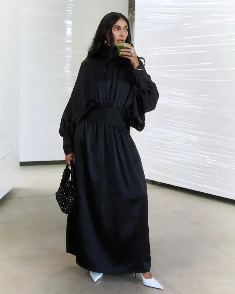 Guest in a long black dress sipping a bright green drink