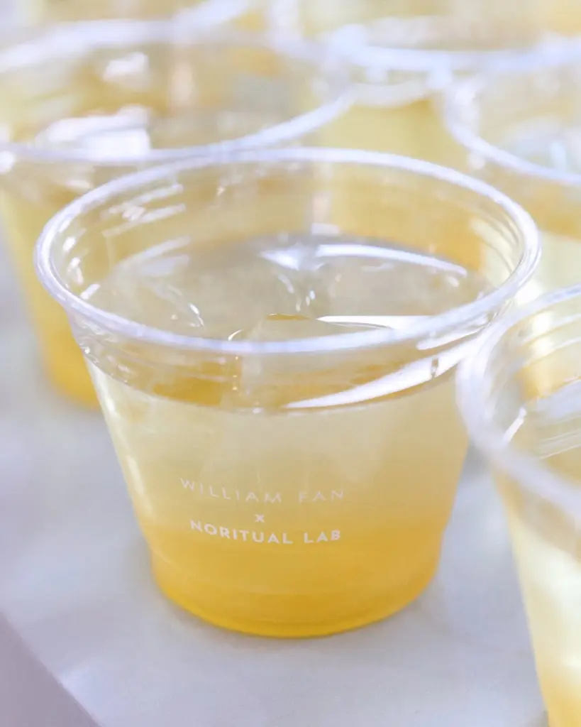 Clear branded cup filled with a pale golden drink and ice