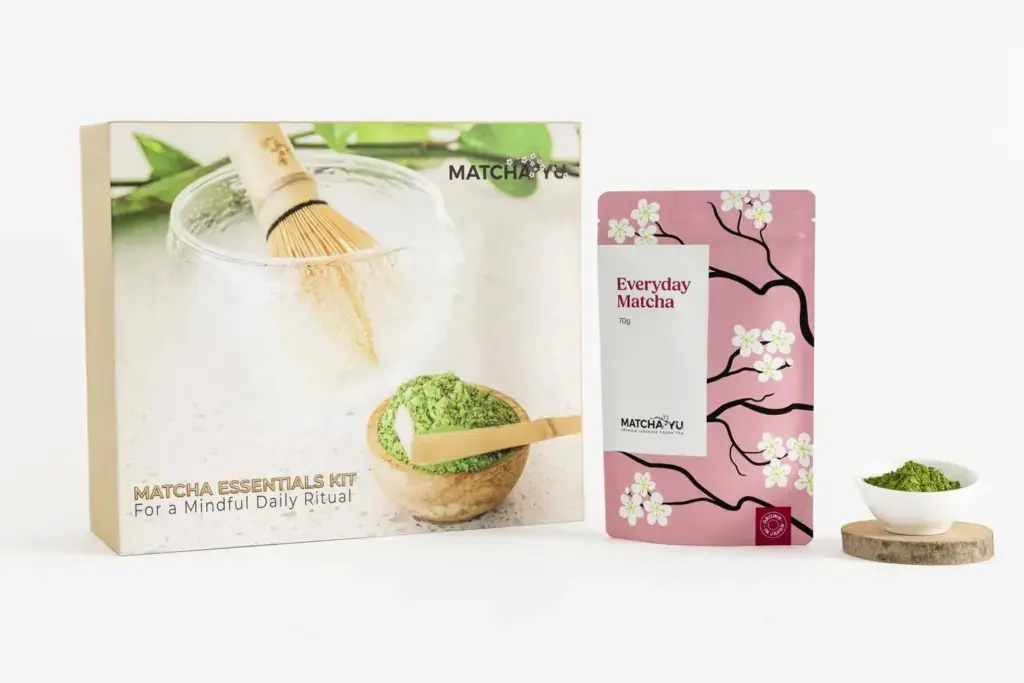 Matcha Yu Tea Essentials Kit box beside a pink 70g Everyday Matcha pouch and a bowl of green powder
