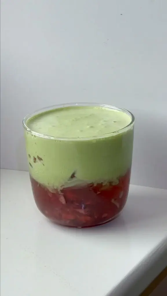Glass with a pale green foamy layer over a red iced drink